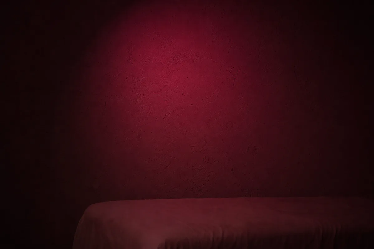 Halo lumineux infrarouge tamisé sur un mur de plâtre brut dans une pièce obscure