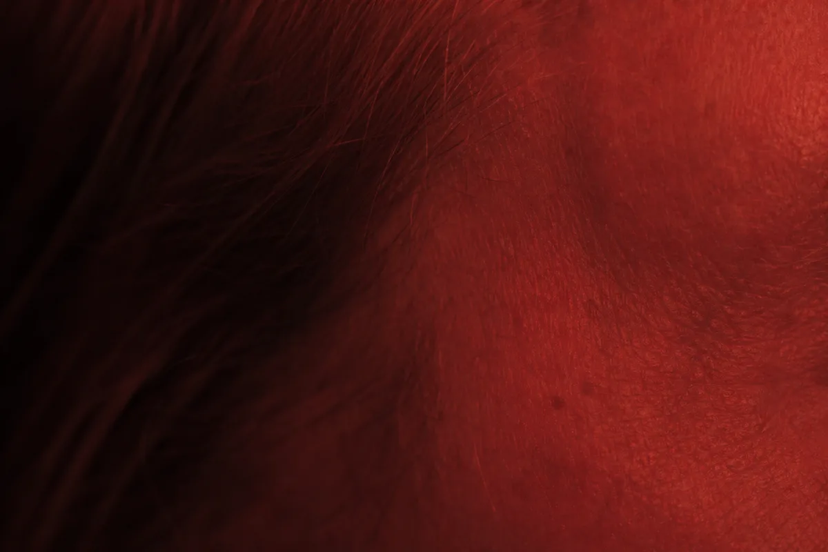 Peau mature au niveau du contour de l&rsquo;œil éclairée par une lumière rouge diffuse dans une pièce sombre
